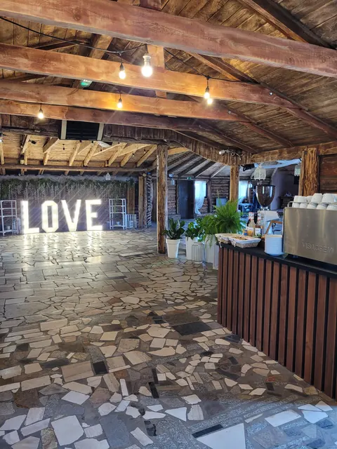 Sala w stodole z napisem LOVE i strefą barową