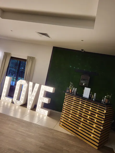 Drewniany bar mobilny i podświetlany napis LOVE na sali weselnej